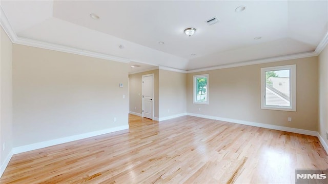 unfurnished room with a tray ceiling, light hardwood / wood-style flooring, a healthy amount of sunlight, and ornamental molding