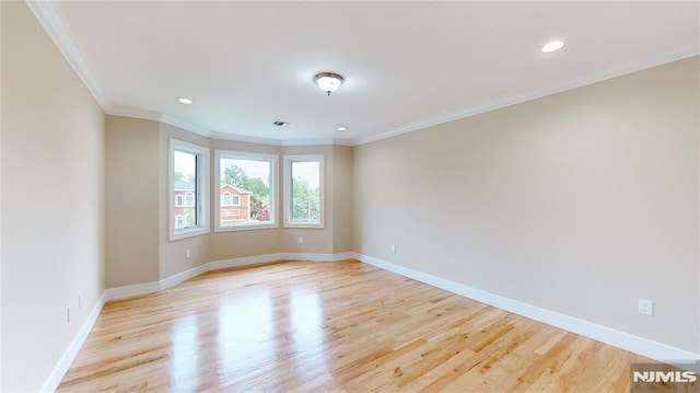 spare room featuring light wood-type flooring and crown molding