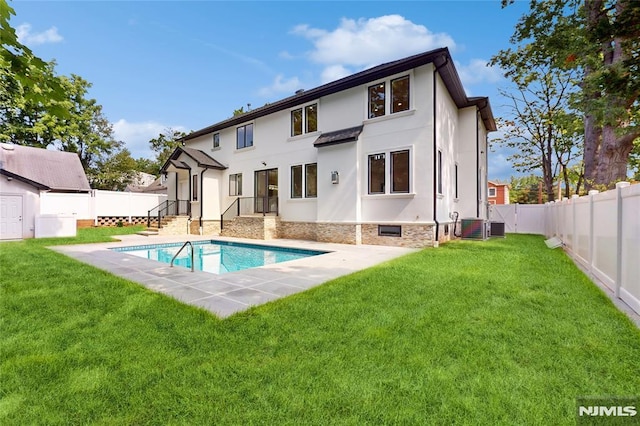 back of property featuring a lawn and a fenced in pool