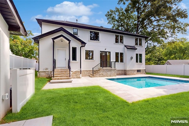 back of property with a lawn and a fenced in pool