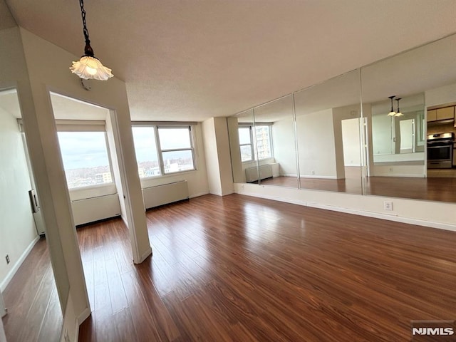 unfurnished living room with hardwood / wood-style flooring, plenty of natural light, and radiator