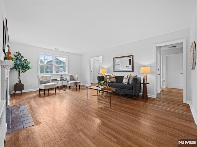 living room featuring hardwood / wood-style floors, radiator heating unit, and a fireplace