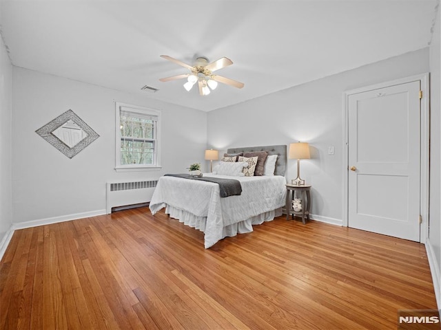 bedroom featuring ceiling fan, light wood-type flooring, and radiator heating unit