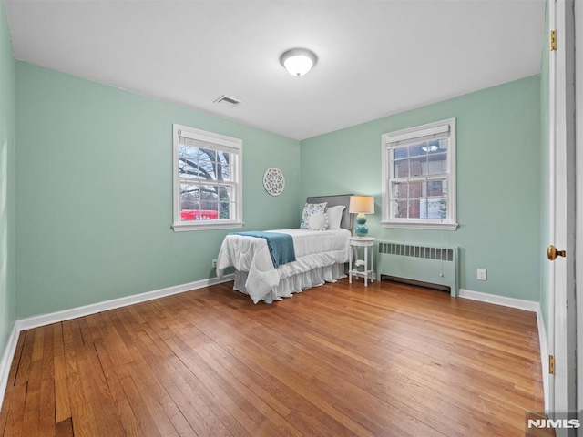 bedroom featuring radiator heating unit and hardwood / wood-style flooring