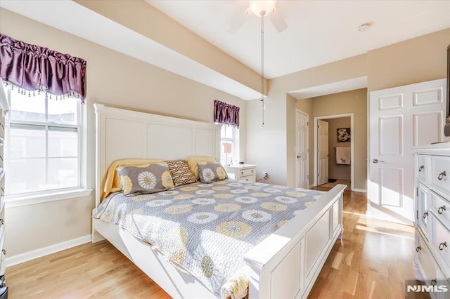 bedroom with ceiling fan, multiple windows, and light hardwood / wood-style flooring