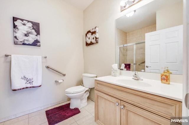 bathroom with a shower with shower door, toilet, vanity, and tile patterned flooring