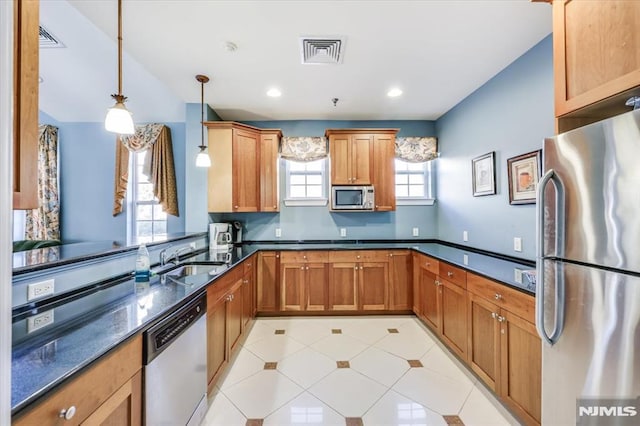 kitchen featuring decorative light fixtures, dark stone countertops, kitchen peninsula, sink, and appliances with stainless steel finishes