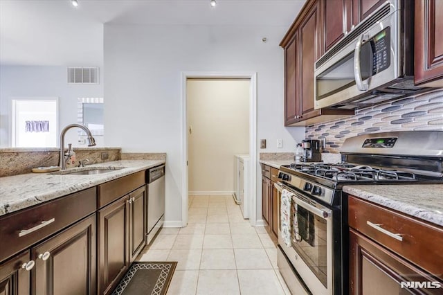 kitchen featuring light tile patterned floors, stainless steel appliances, decorative backsplash, light stone countertops, and sink