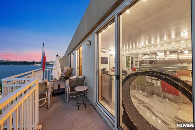 balcony at dusk featuring a water view