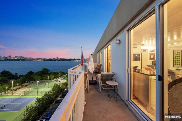 balcony at dusk featuring a water view