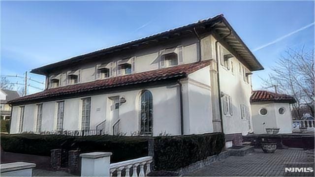 back of property with a tiled roof and stucco siding