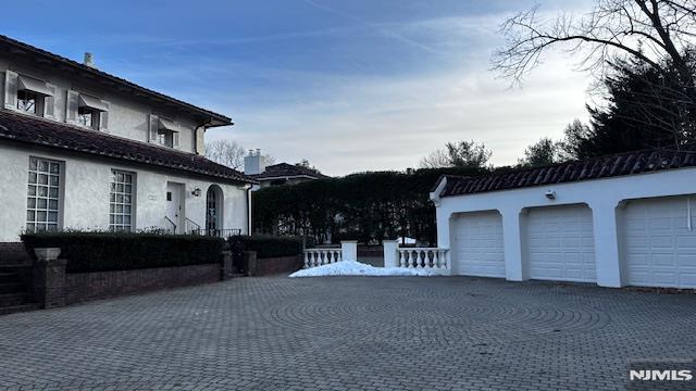 view of side of property featuring an outbuilding, stucco siding, and a garage