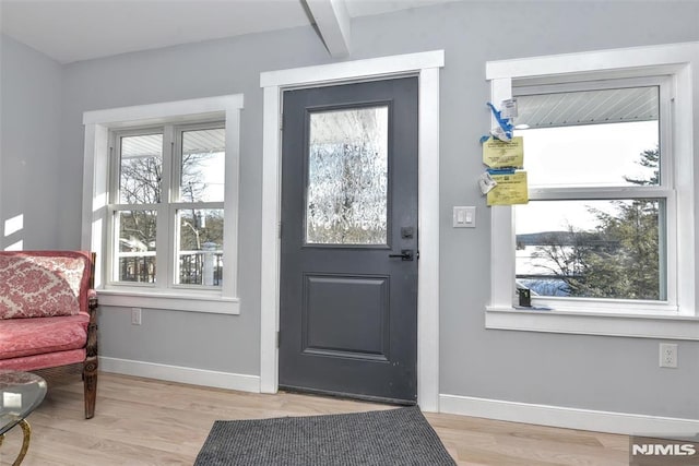 doorway featuring beam ceiling and light wood-type flooring