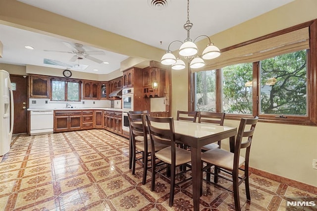 dining room with ceiling fan with notable chandelier and sink