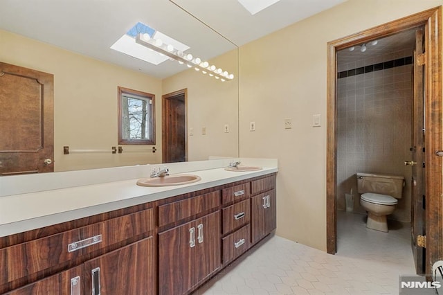 bathroom featuring toilet, vanity, a skylight, and tile patterned floors