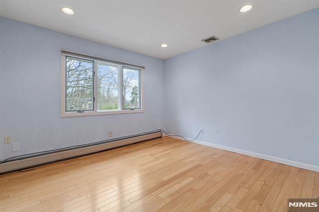 empty room with light wood-type flooring and baseboard heating