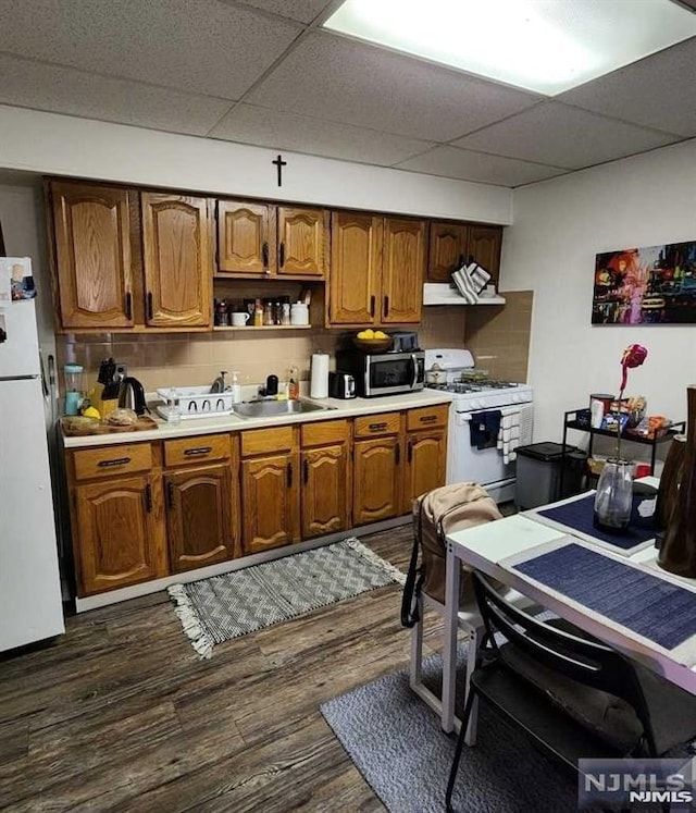 kitchen featuring a paneled ceiling, white appliances, exhaust hood, sink, and dark hardwood / wood-style floors