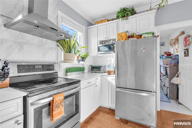 kitchen with white cabinets, stainless steel appliances, extractor fan, and ornamental molding