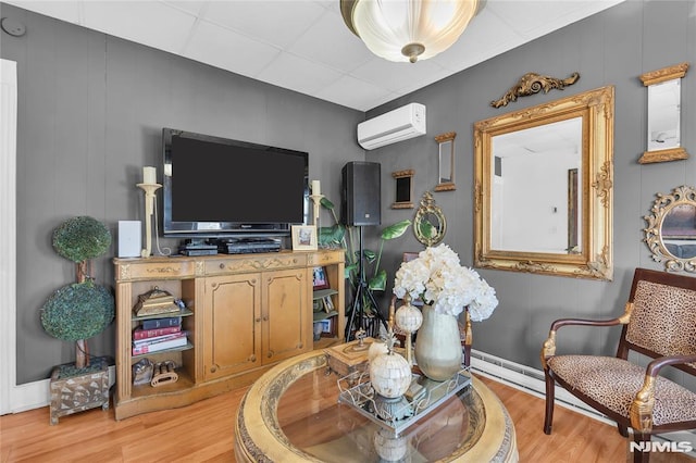 living area featuring light hardwood / wood-style floors, an AC wall unit, and a drop ceiling