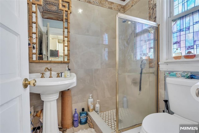 bathroom featuring toilet, tile walls, and a shower with shower door