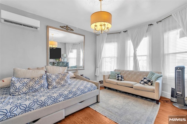 bedroom featuring wood-type flooring, a wall mounted air conditioner, and an inviting chandelier