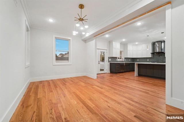 unfurnished living room featuring sink, ceiling fan, ornamental molding, and light hardwood / wood-style floors