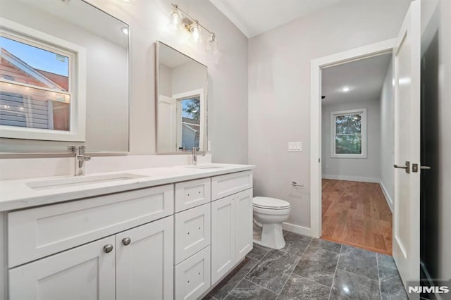 bathroom with a healthy amount of sunlight, vanity, and toilet