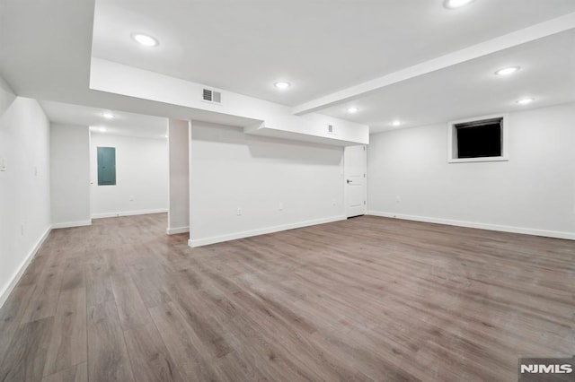 basement featuring electric panel and light hardwood / wood-style floors