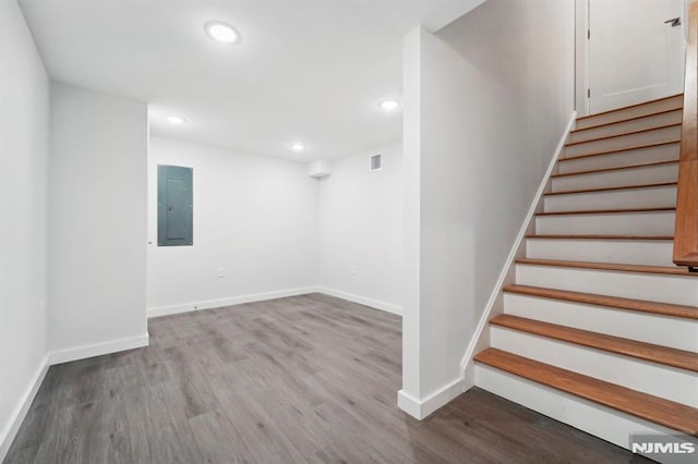 staircase featuring electric panel and hardwood / wood-style floors