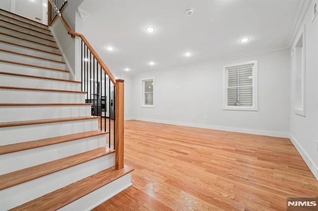 stairs with ornamental molding and hardwood / wood-style floors