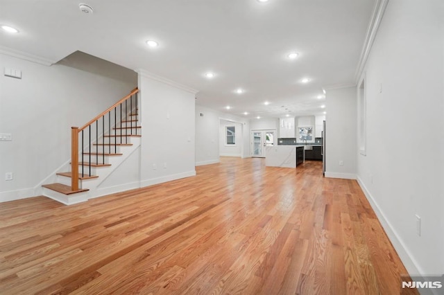 unfurnished living room featuring light wood-type flooring and crown molding