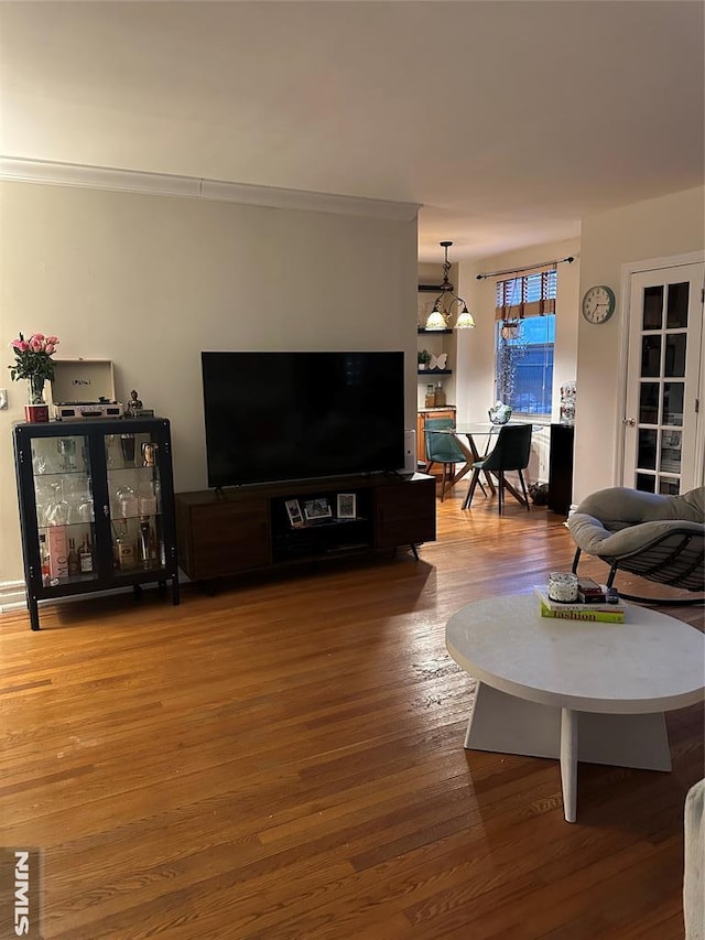 living room featuring crown molding, a chandelier, and hardwood / wood-style floors