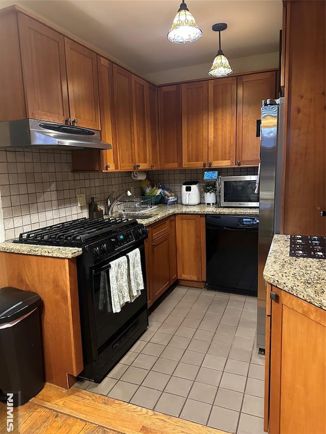 kitchen featuring sink, light tile patterned floors, backsplash, hanging light fixtures, and black appliances