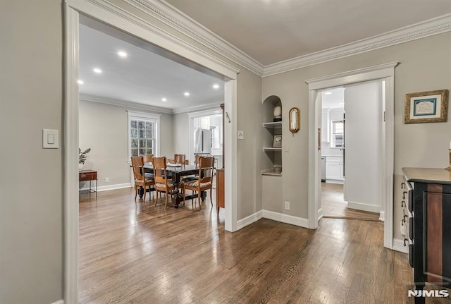 dining room featuring hardwood / wood-style floors, built in features, and crown molding