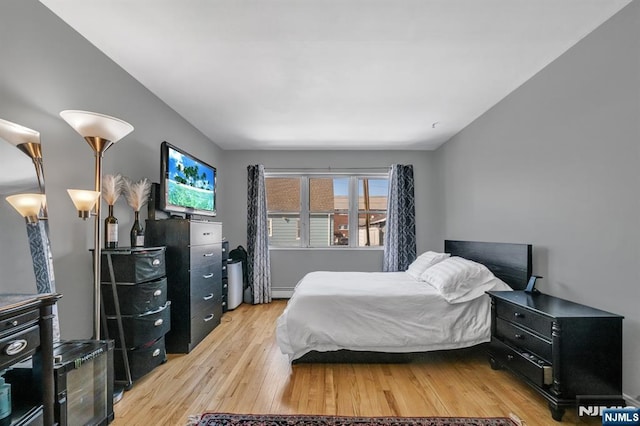 bedroom featuring a baseboard heating unit and light hardwood / wood-style floors