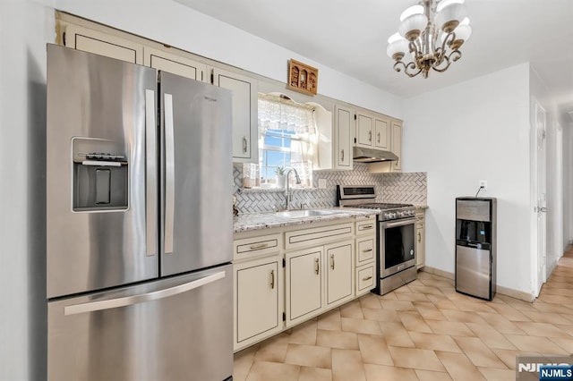 kitchen featuring sink, light stone counters, appliances with stainless steel finishes, cream cabinets, and decorative backsplash