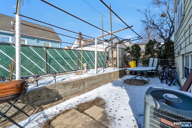 snow covered patio with cooling unit and area for grilling