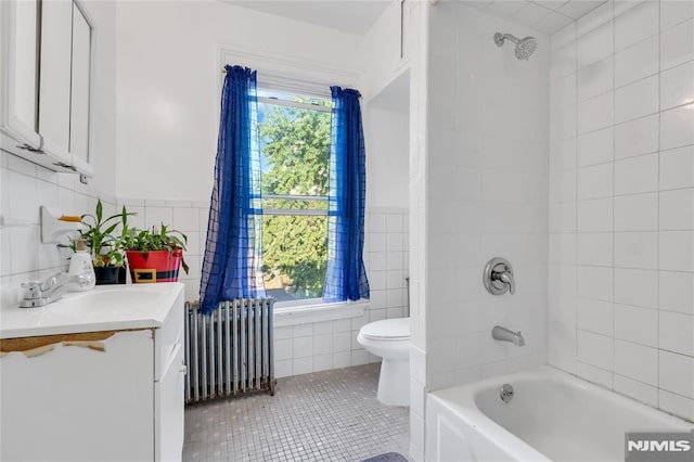 full bathroom with radiator heating unit, tiled shower / bath combo, tile patterned floors, toilet, and vanity