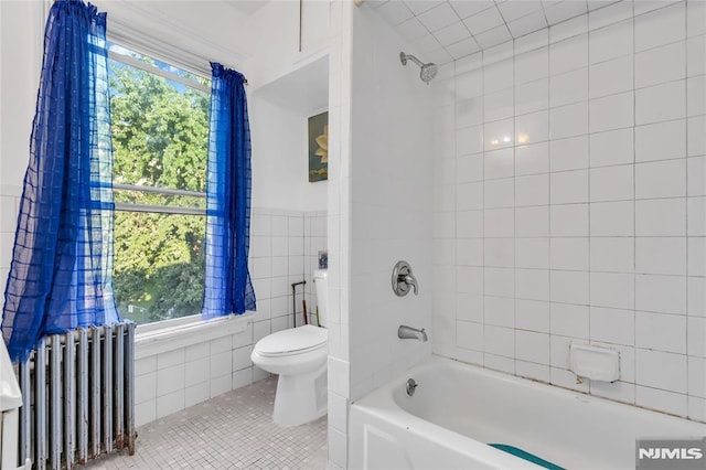 bathroom featuring tile patterned floors, radiator, a healthy amount of sunlight, and tile walls