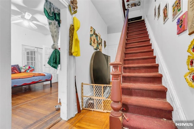 stairs with wood-type flooring and ceiling fan