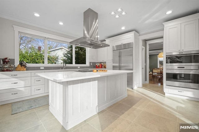 kitchen featuring a center island, crown molding, appliances with stainless steel finishes, white cabinetry, and island exhaust hood