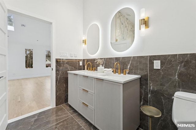 bathroom with tile walls, toilet, and vanity