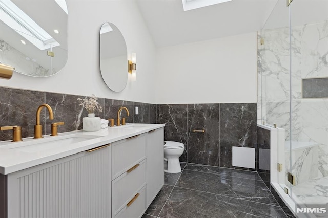 bathroom with toilet, vanity, lofted ceiling with skylight, and a shower with shower door