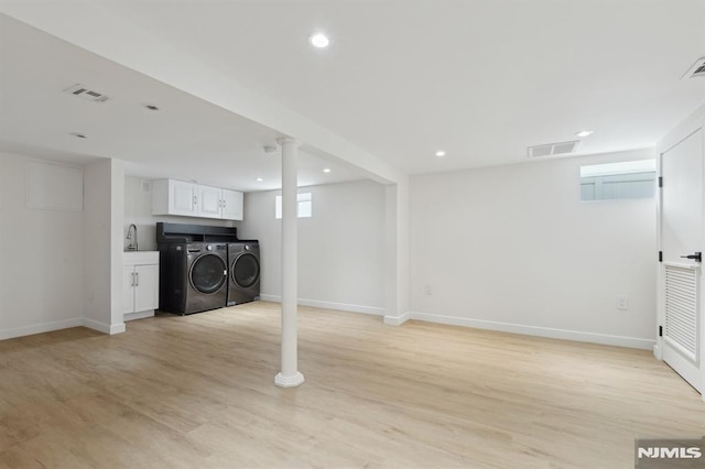 basement with sink, independent washer and dryer, and light wood-type flooring