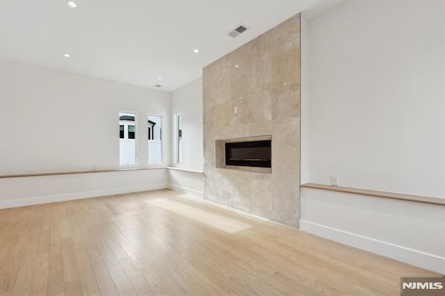 unfurnished living room with light hardwood / wood-style floors and a large fireplace