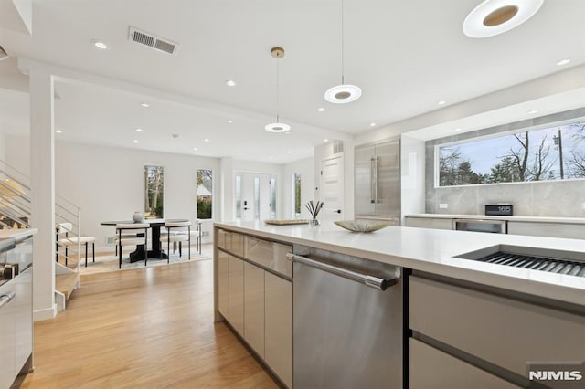 kitchen featuring light wood-type flooring, pendant lighting, and stainless steel dishwasher