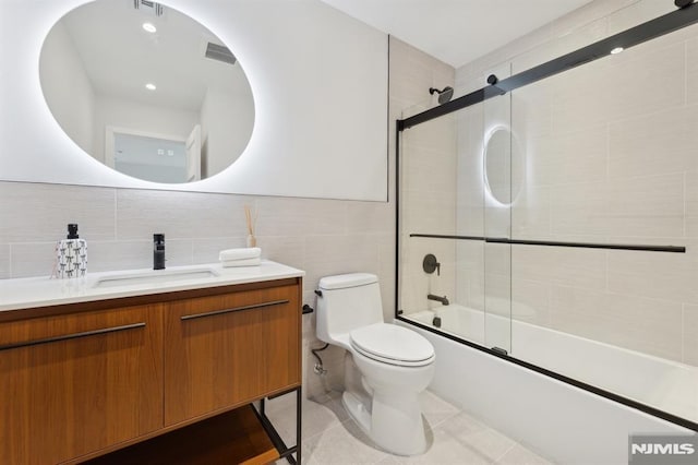 full bathroom with toilet, bath / shower combo with glass door, tile walls, vanity, and decorative backsplash