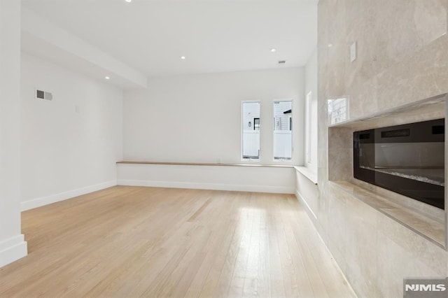 unfurnished living room with a fireplace and light hardwood / wood-style floors