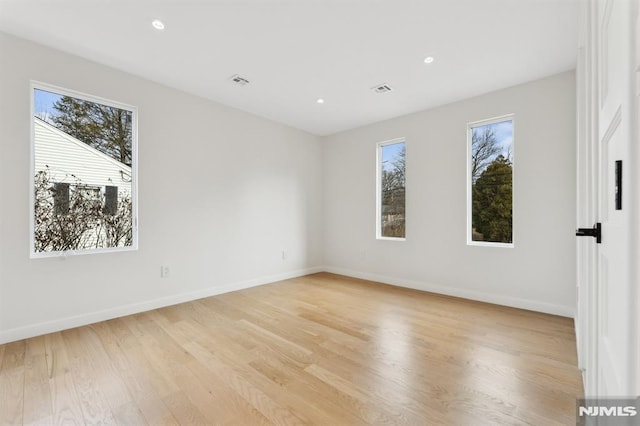 spare room featuring a healthy amount of sunlight and light hardwood / wood-style flooring