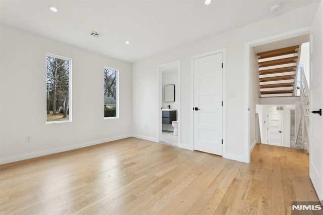 unfurnished bedroom featuring ensuite bathroom and light wood-type flooring